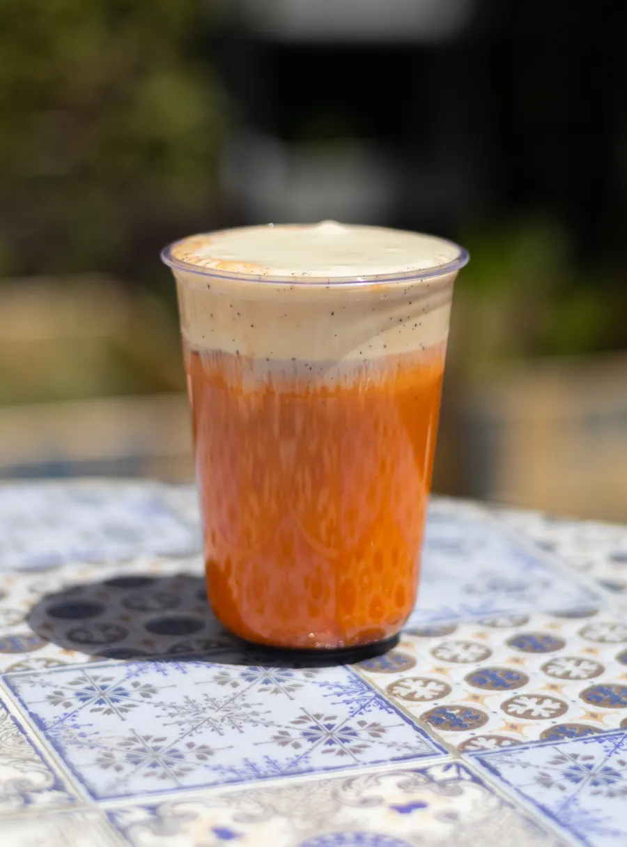 Iced drink with a cream top over an orange body, in natural light