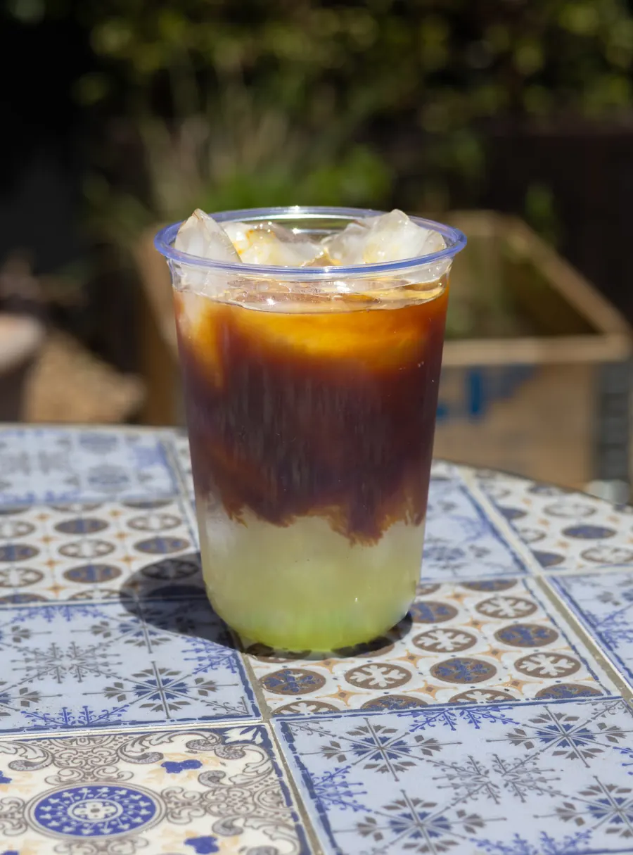 Espresso over ice and a green citrus layer, on a tiled table outdoors